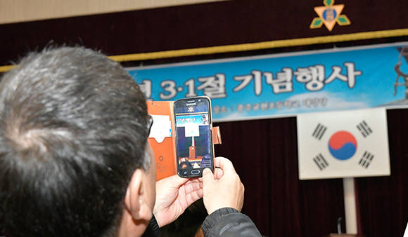 3.1절 기념행사에 참석한 시민이 단상의 태극기를 찍고있다.