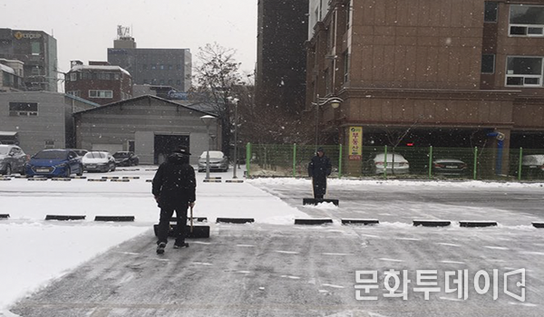 주차장에 쌓인 눈을 치우는 작업을 하고 있다