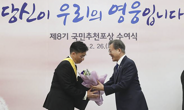 이국종 아주대병원 권역외상센터 소장(왼쪽)이 문재인대통령(오른쪽)으로부터 무궁화장과 꽃다발을 받고 있다