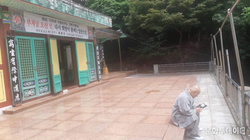 기연스님이 상연사 법당 앞에서 스마트 폰으로 외국의 제자들과 안부를 묻고 있다.