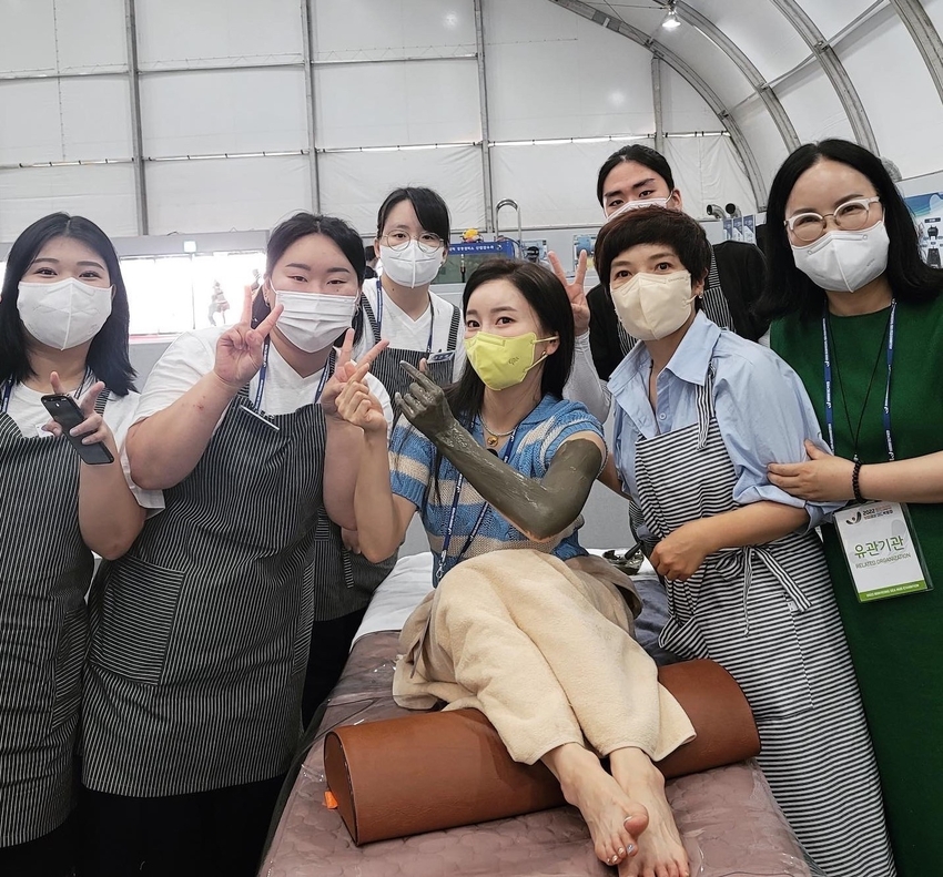 2022 보령머드박람회 체험부스가 개설된 충남도립대학교에서 한 관람객이 머드를 바르고 운영진과 포즈를 취했다.