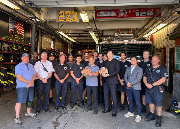 FDNY 소방대원이 BBQ에 전달한 감사패를 들고 기념촬영을 하고 있다.<br>
